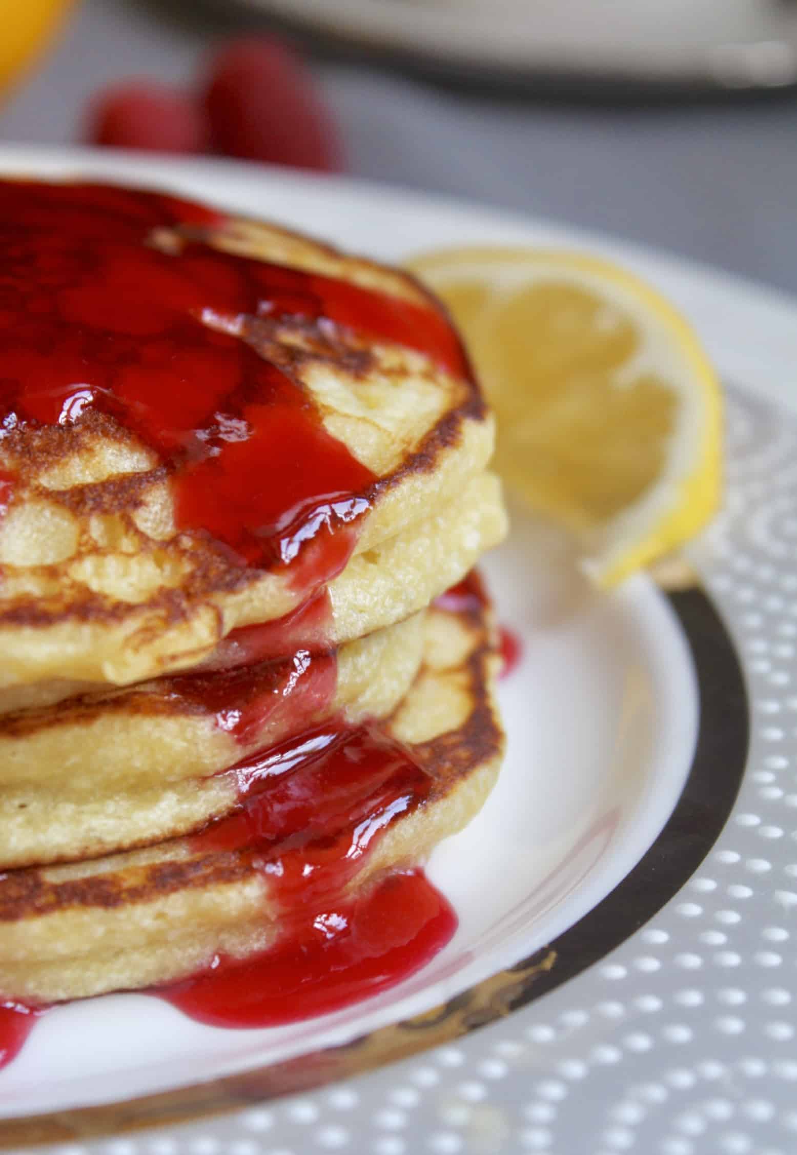 close up of lemon ricotta pancakes with raspberry syrup dripping down