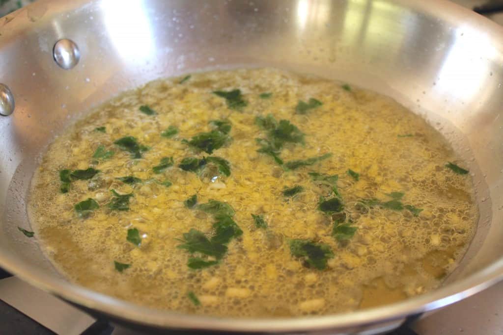 adding wine to garlic and butter shrimp spaghetti