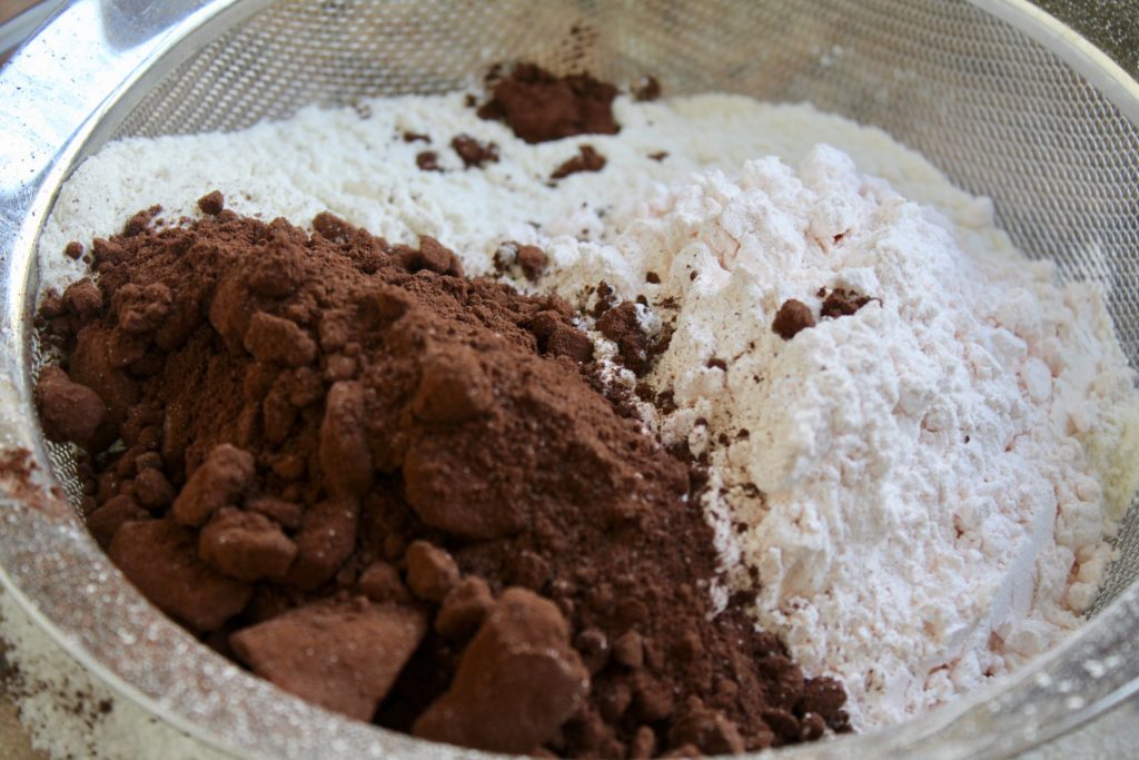 sifting flour and cocoa powder to make Bourbon biscuits