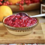 cranberry orange sauce with citrus in background and Happy Thanksgiving in foreground