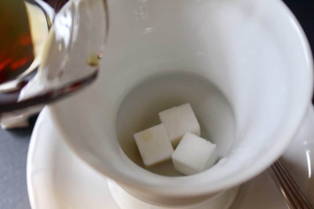 pouring brandy over sugar cubes in cup