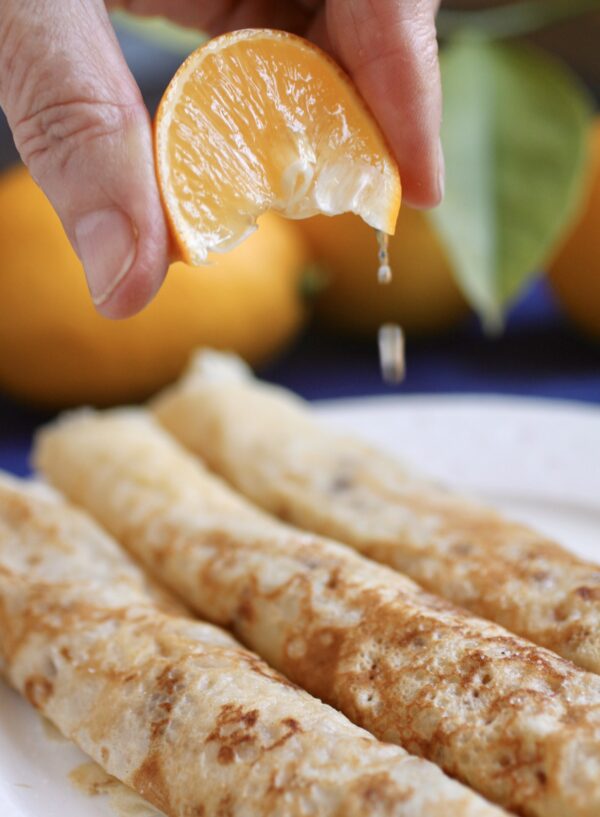 squeezing lemon on British pancakes on a plate