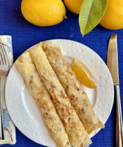 3 shrove Tuesday pancakes on a plate with lemons