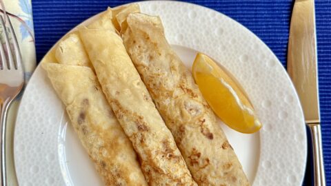 3 shrove Tuesday pancakes on a plate with lemons