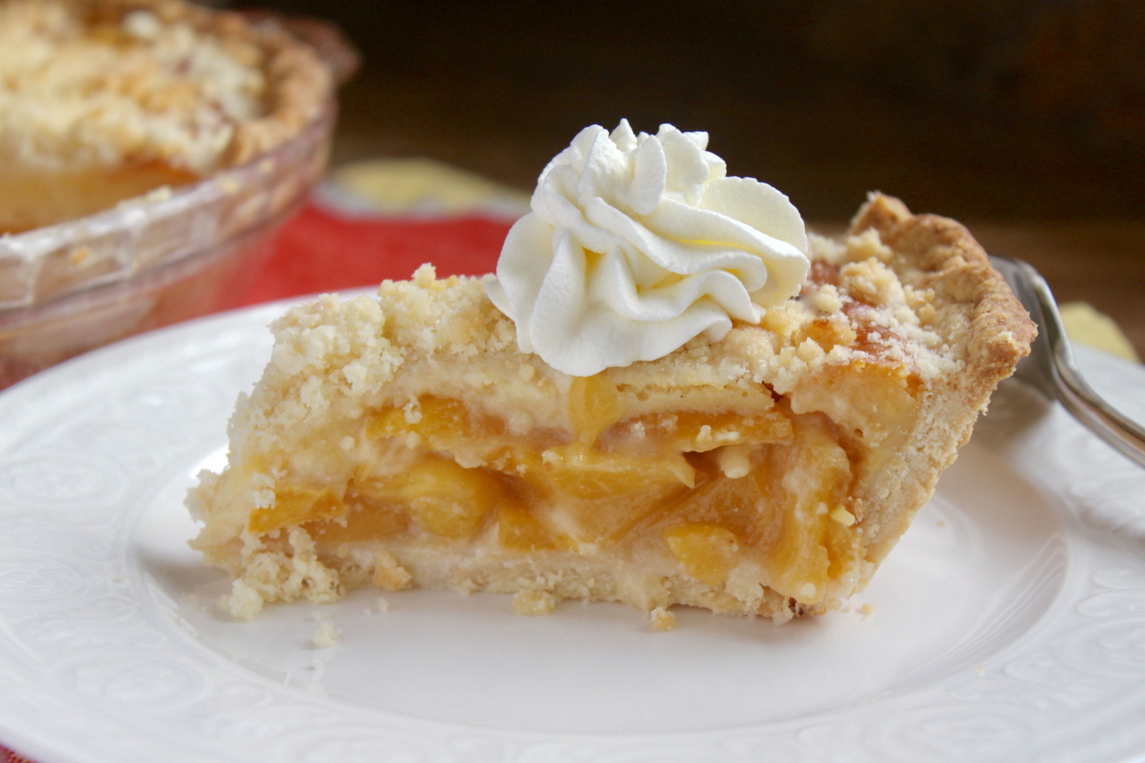 Slice of custard peach pie with whipped cream