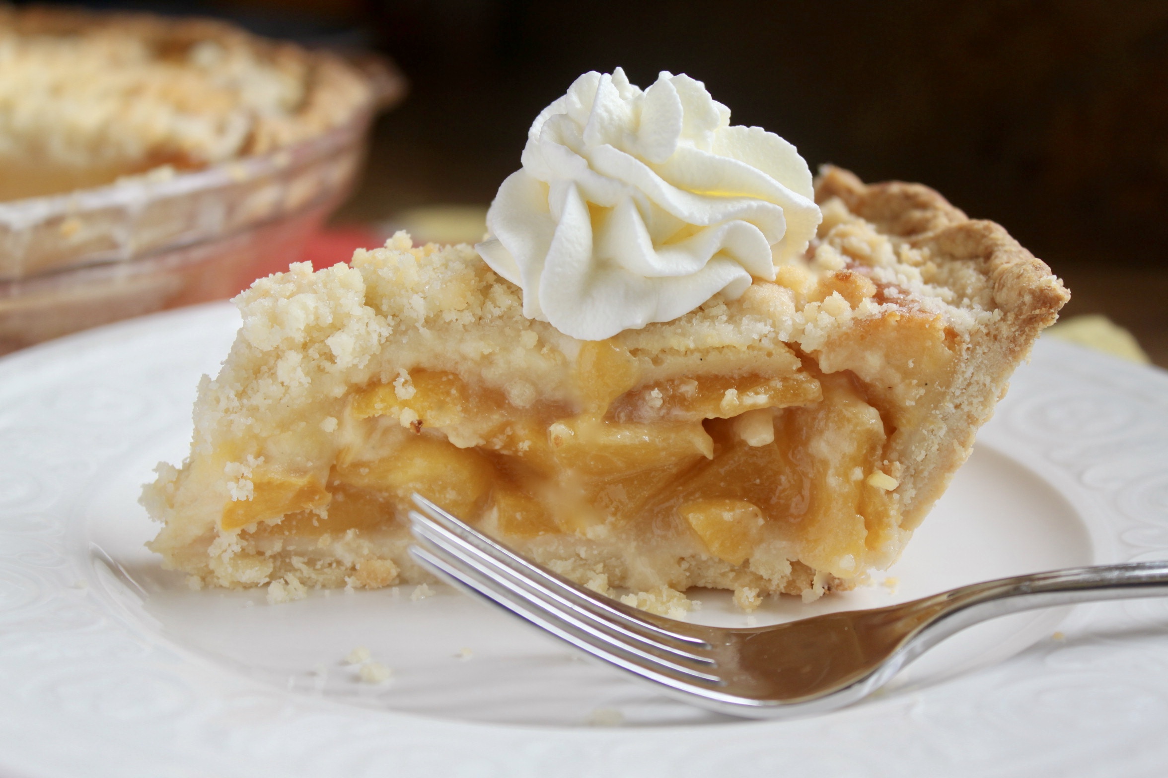 Slice of custard peach pie with cream