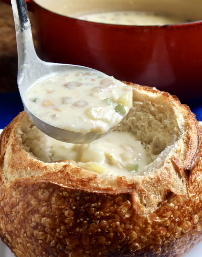 San Francisco clam chowder recipe ladling into sourdough boule