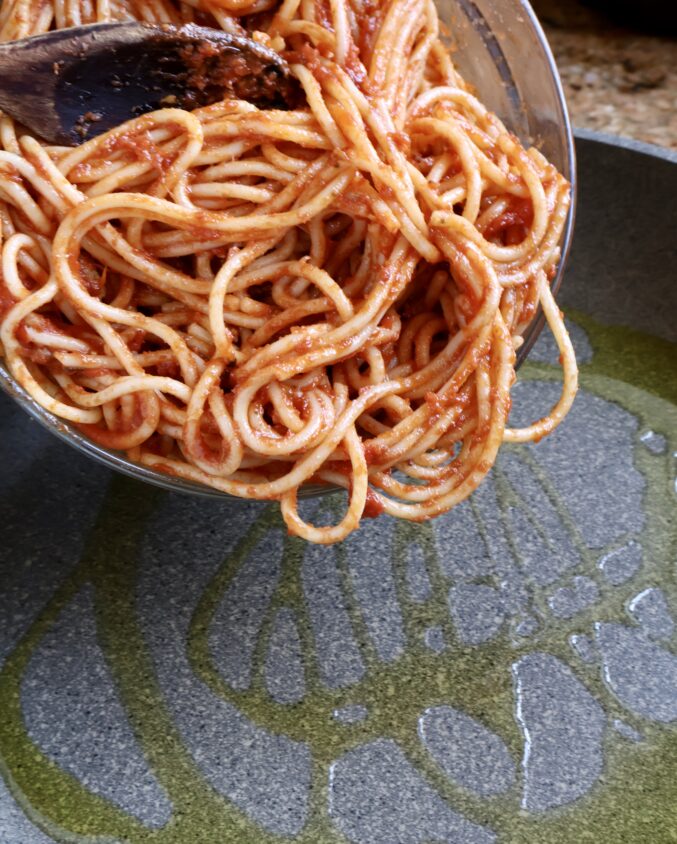 adding spaghetti to pan