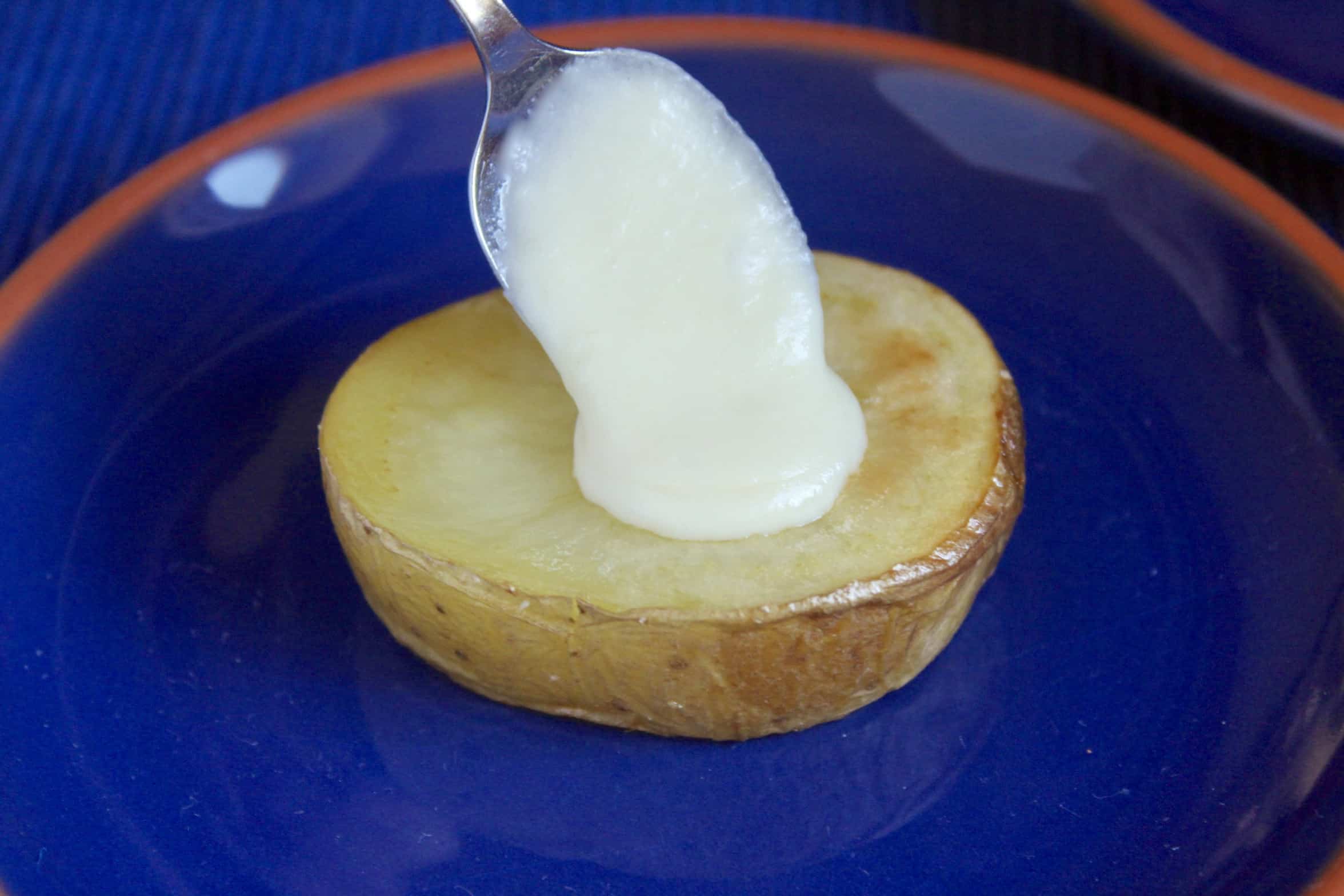 spooning melted Manchego cream onto potato