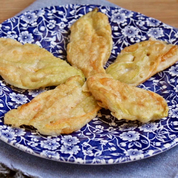 5 fried Italian zucchini blossoms on a floral plate