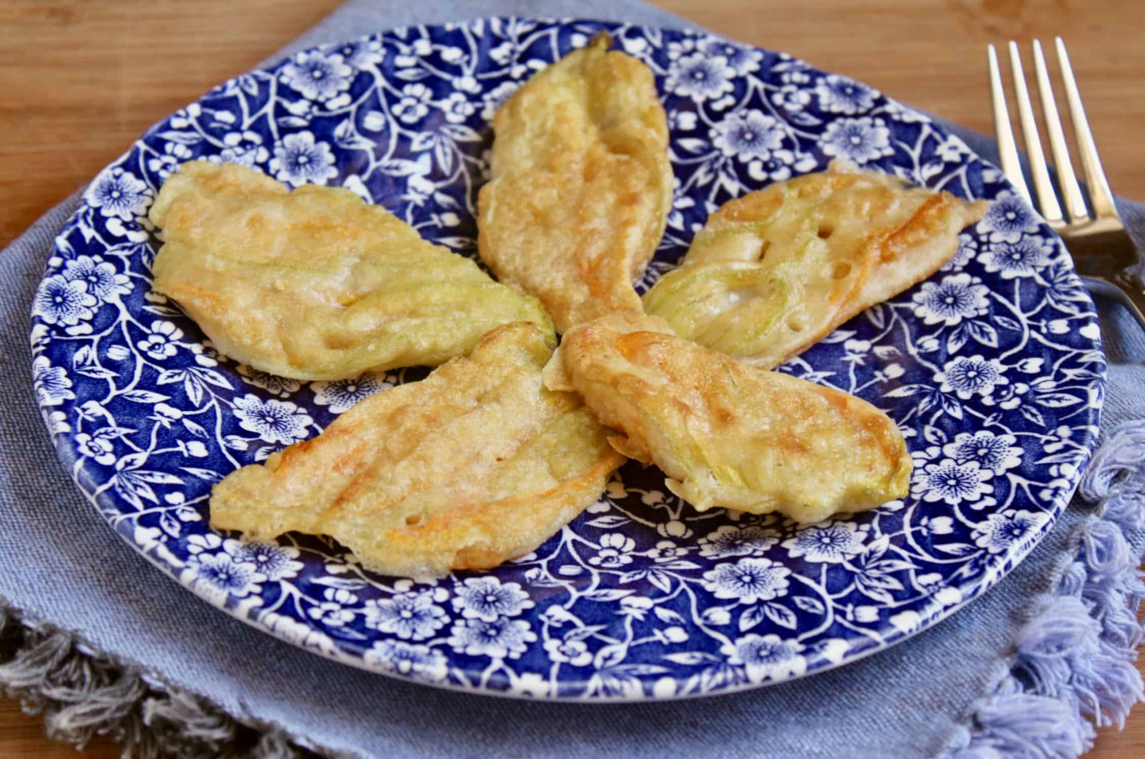 5 fried Italian zucchini blossoms on a floral plate