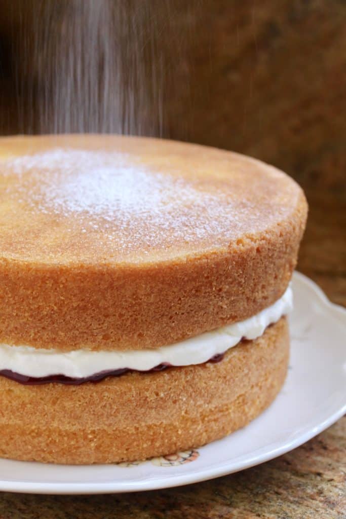 dusting a victoria sponge cake with sugar