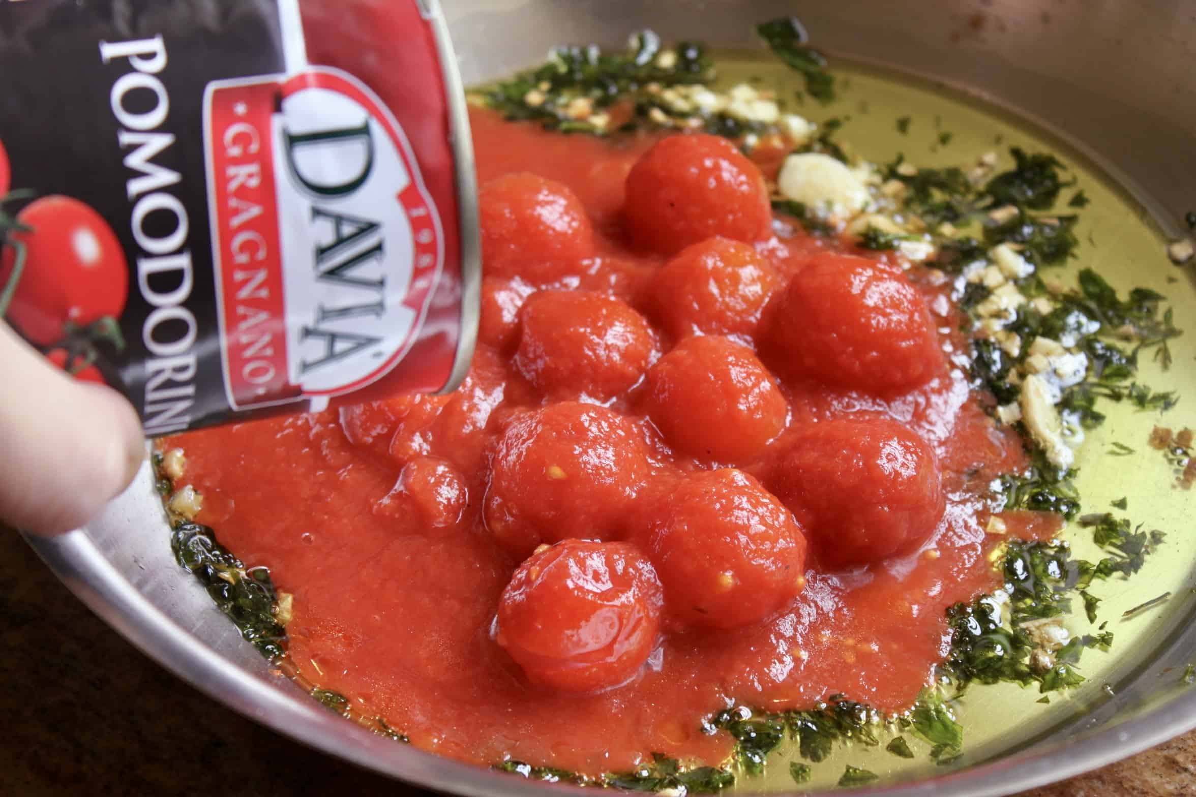 pouring davia tomatoes in a pan