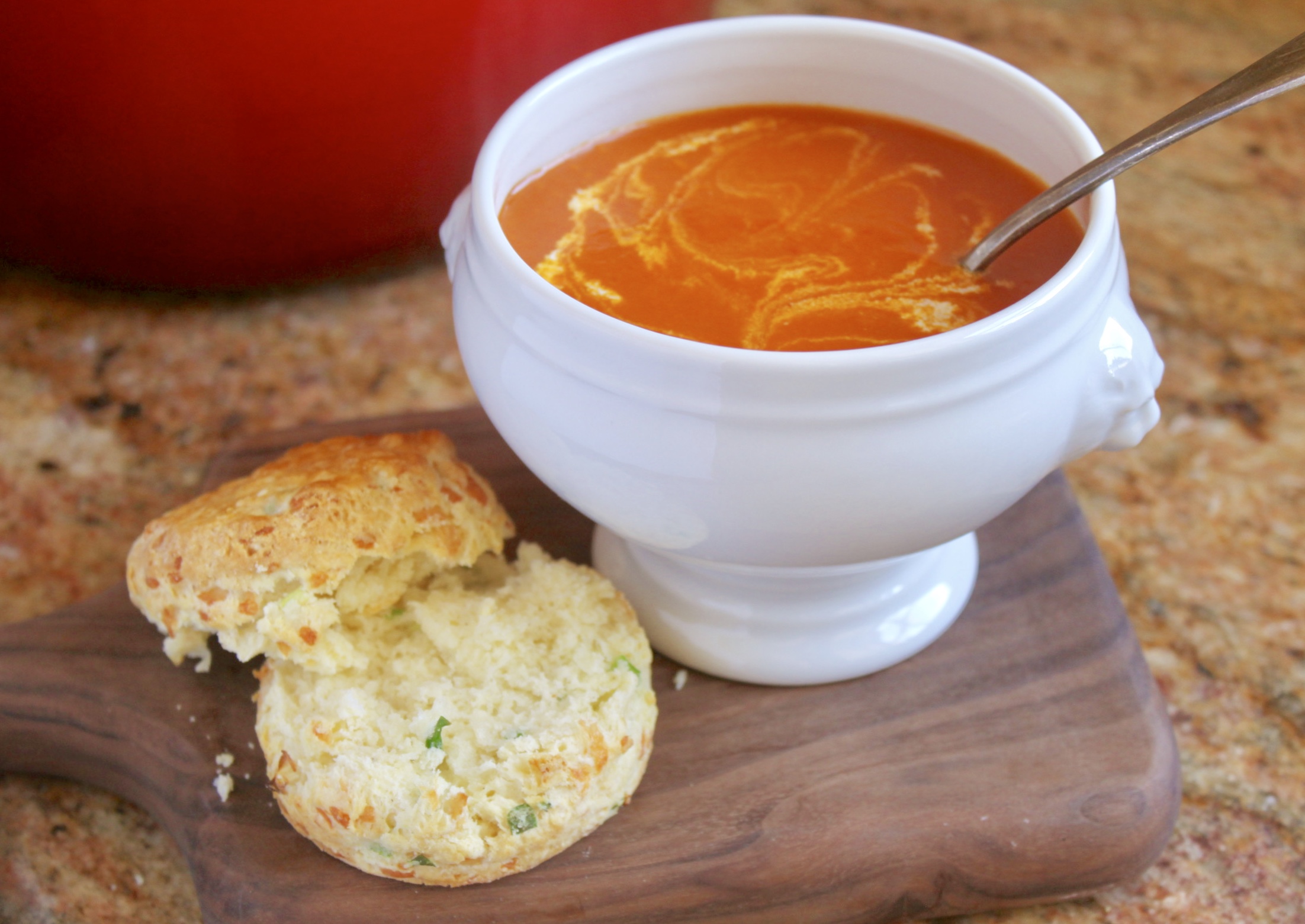 Tomato turmeric soup in a bowl with a cheese scone