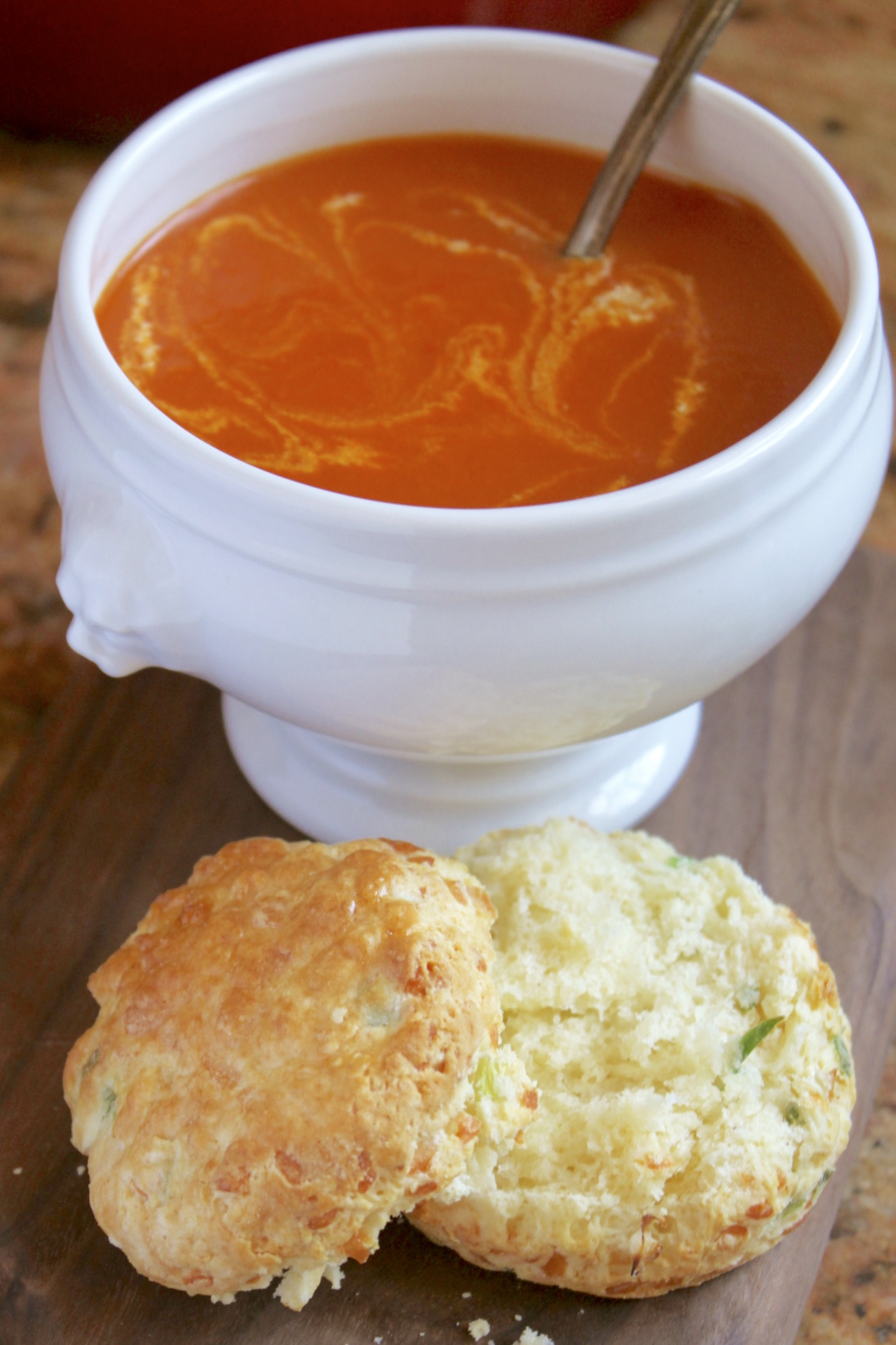 Tomato turmeric soup in a bowl with a cheese scone