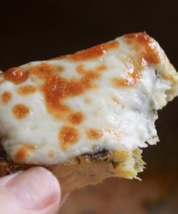 handheld piece of grilled polenta with cheese, bitten