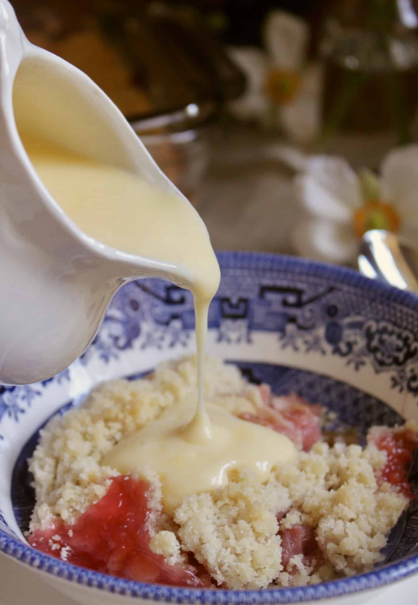 pouring custard onto rhubarb crumble