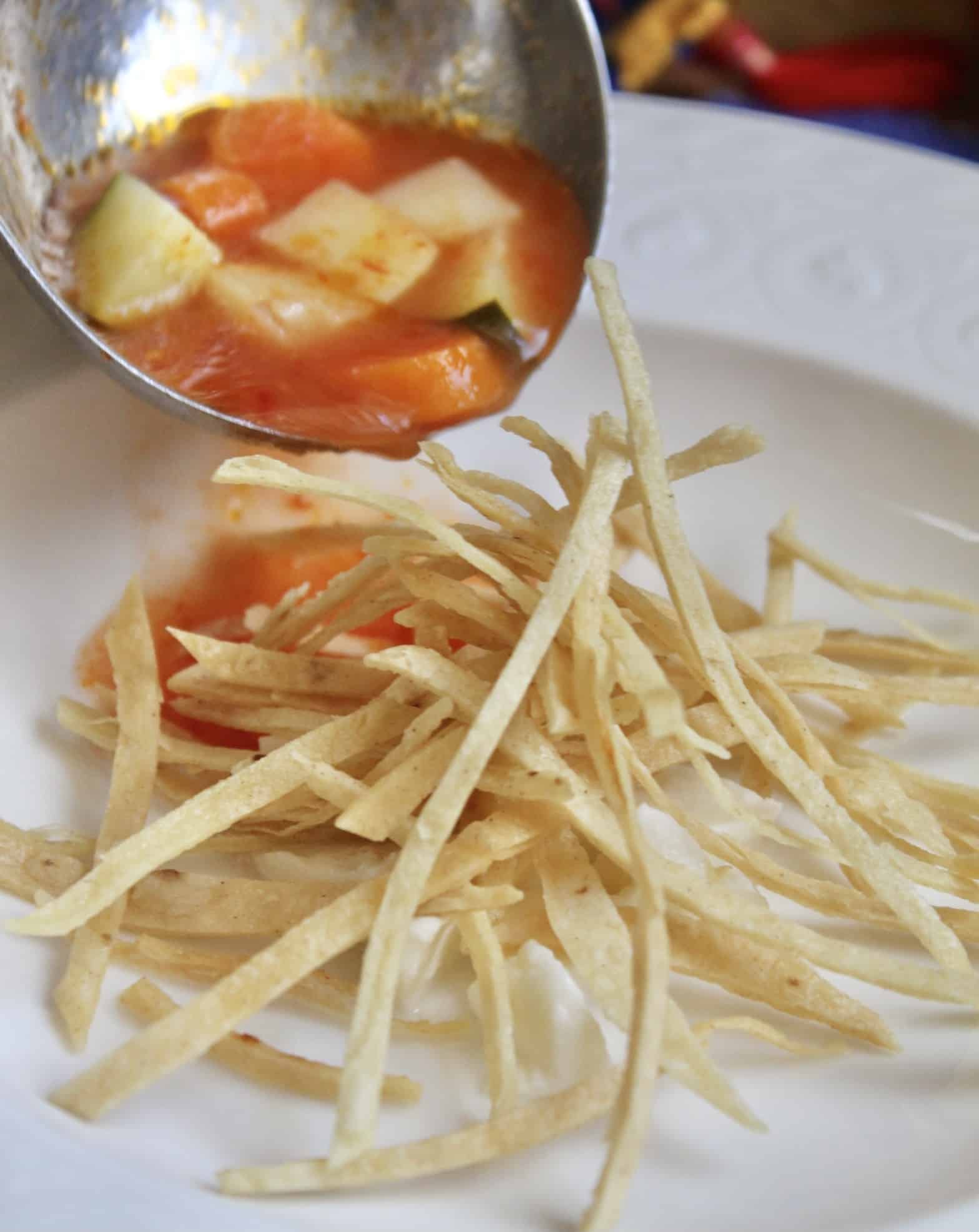 ladling tortilla soup into the bowl