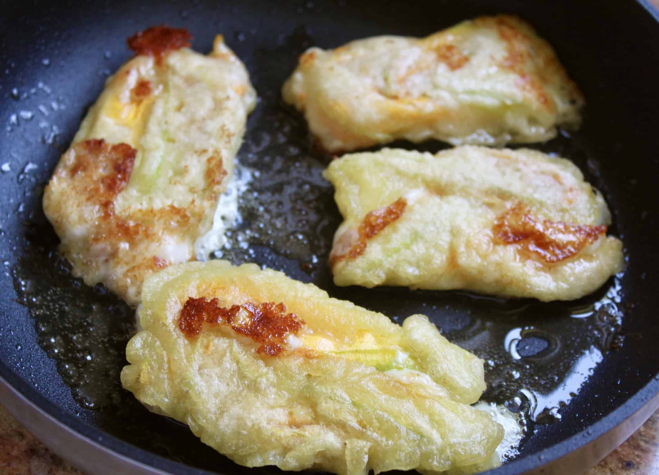 fried zucchini flowers stuffed with cheese in pan