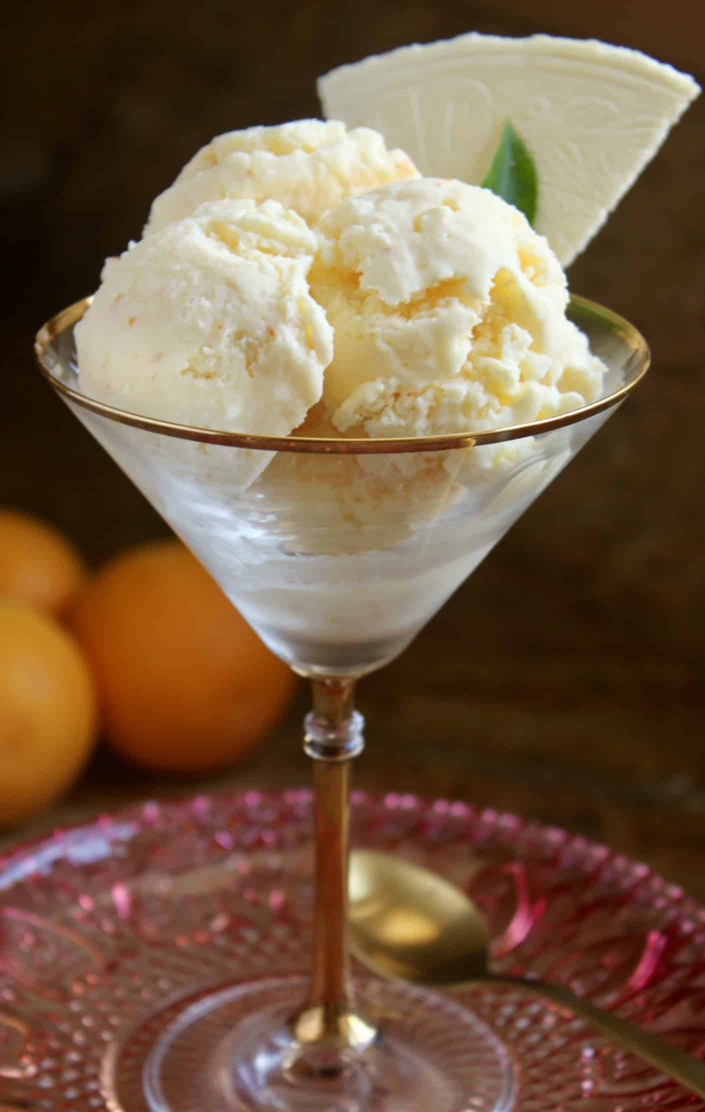 three scoops of orange ice cream and a wafer in a martini glass