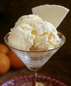 three scoops of orange ice creama and a wafer in a martini glass