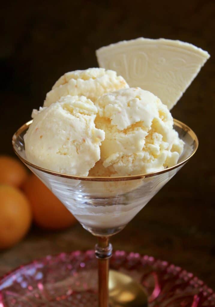 three scoops of orange ice creama and a wafer in a martini glass