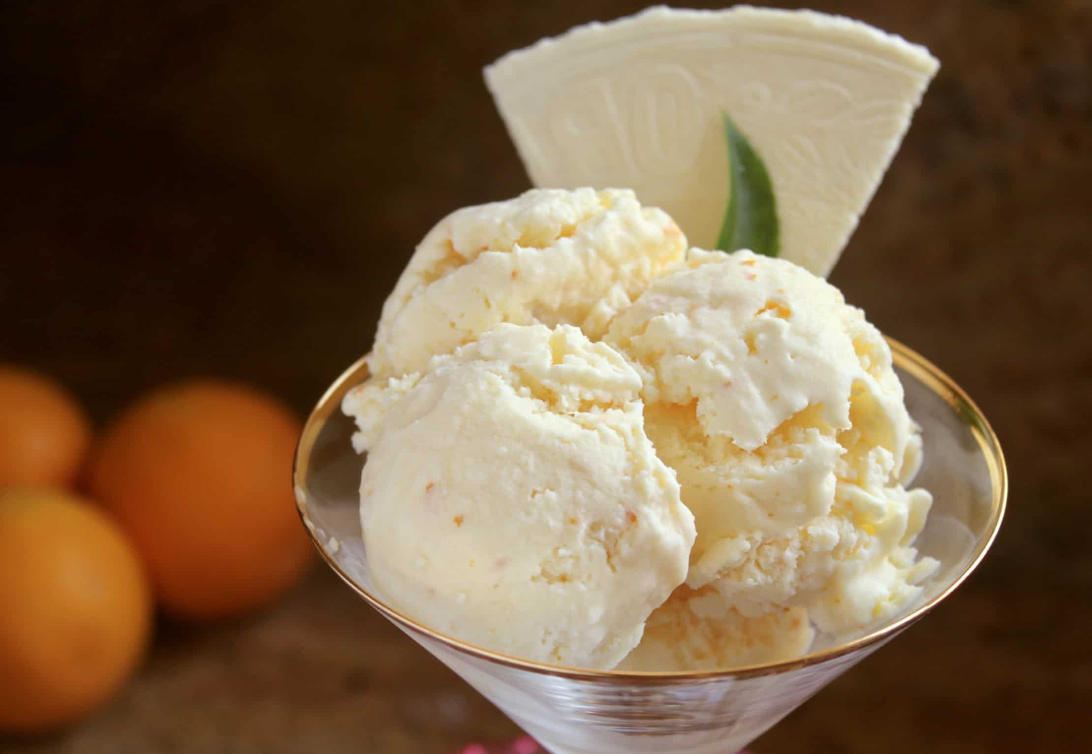 three scoops of orange ice cream and a wafer in a martini glass