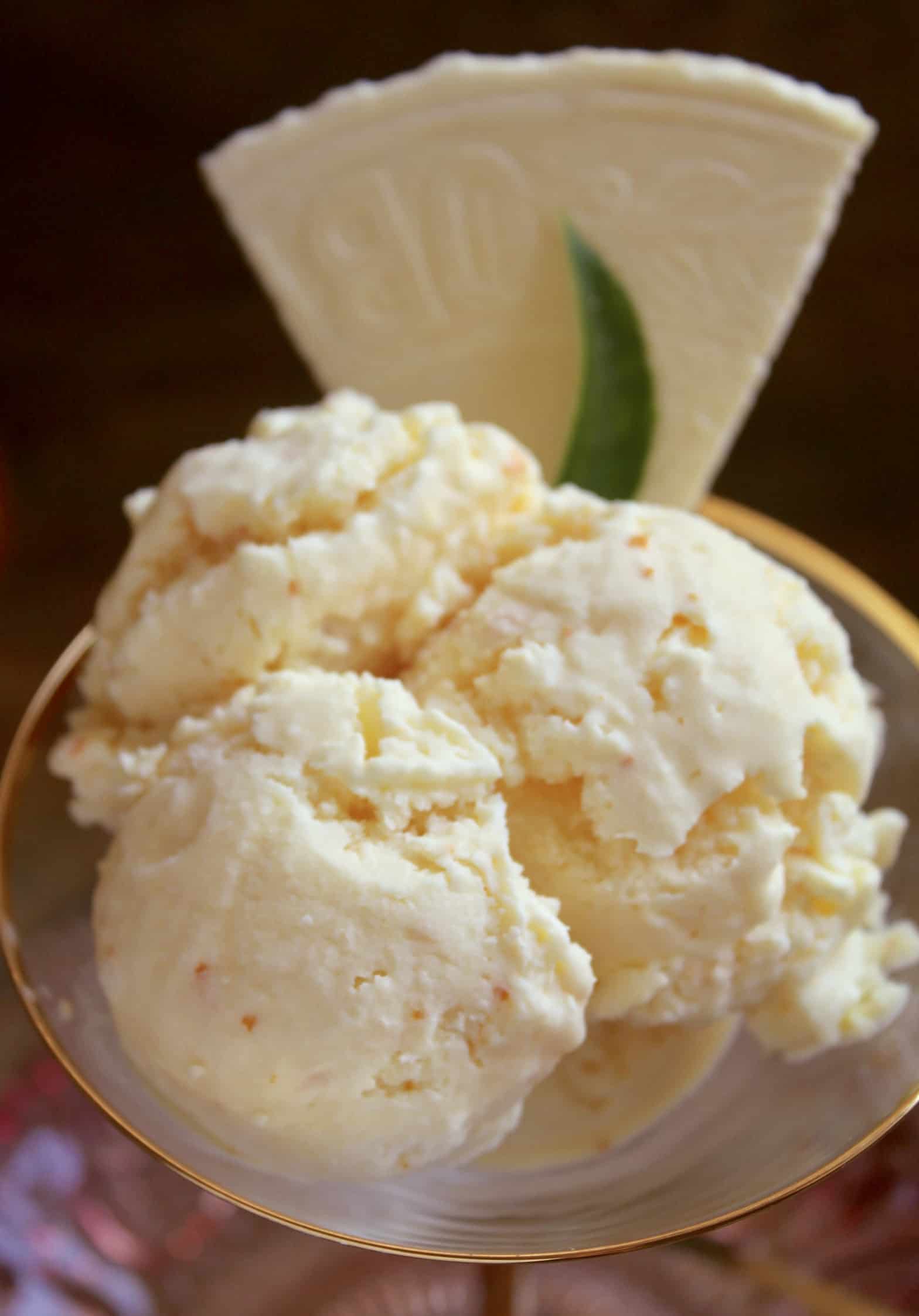 three scoops of orange ice cream and a wafer in a martini glass