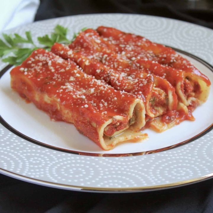 3 manicotti on a plate with parsley