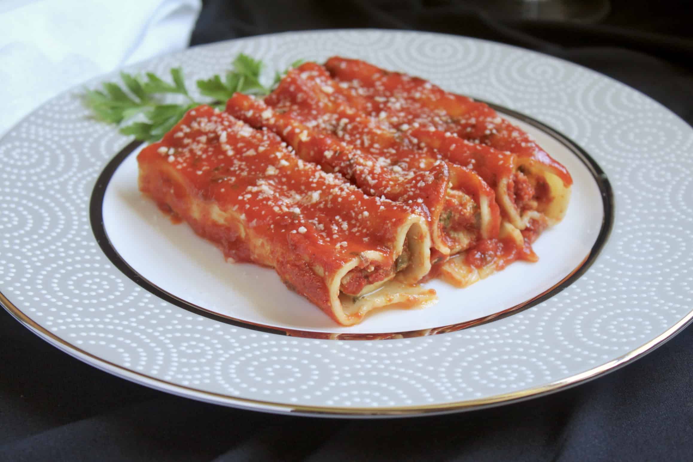3 manicotti on a plate with parsley