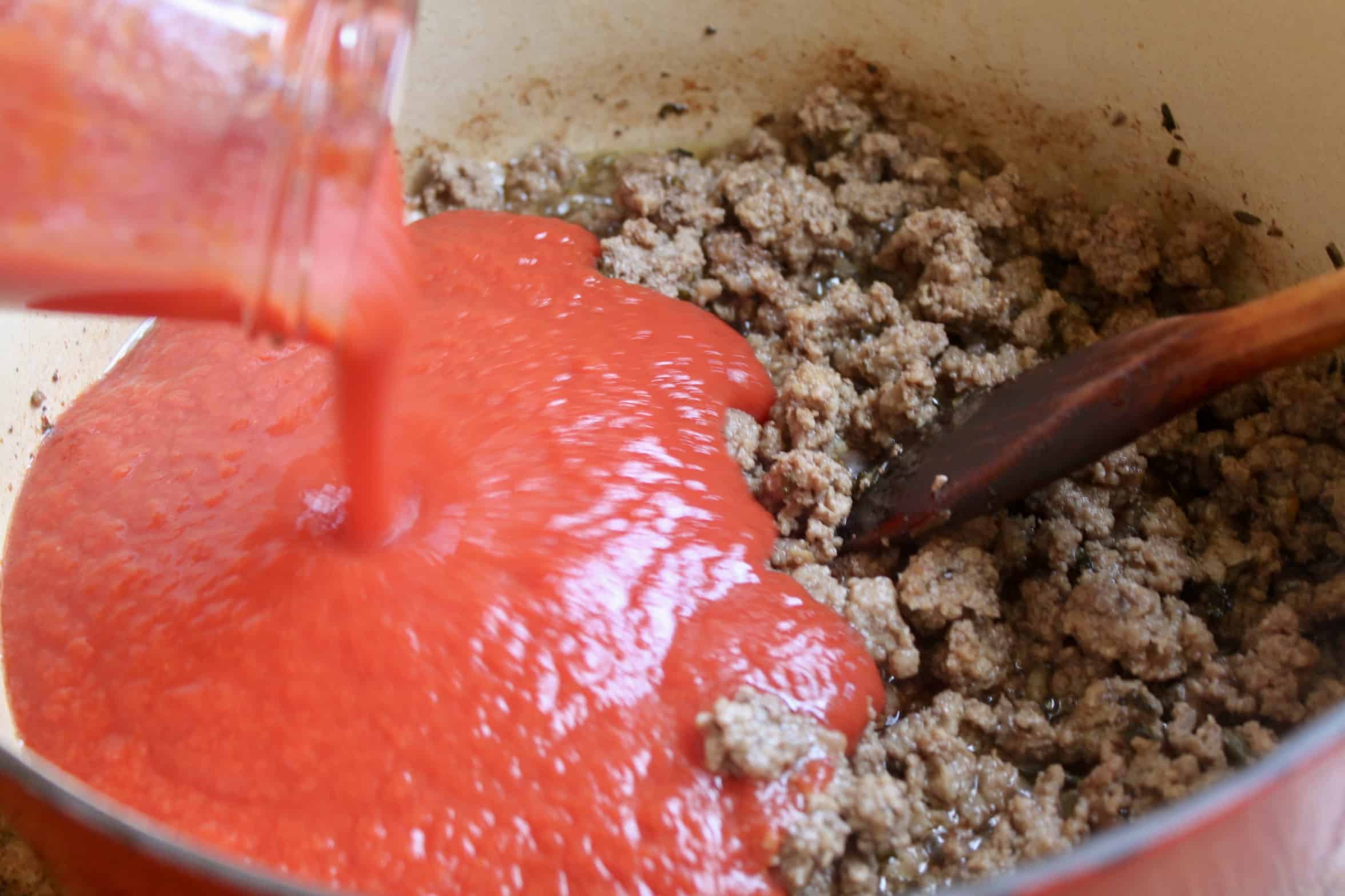 adding sauce to ground beef in pot