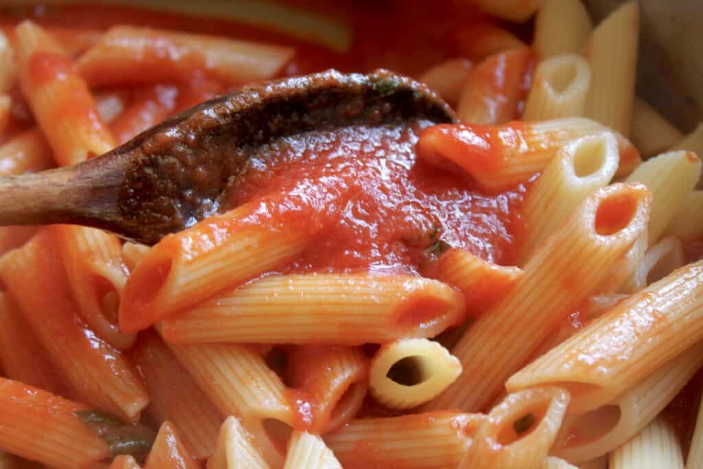 mixing sauce with penne pasta