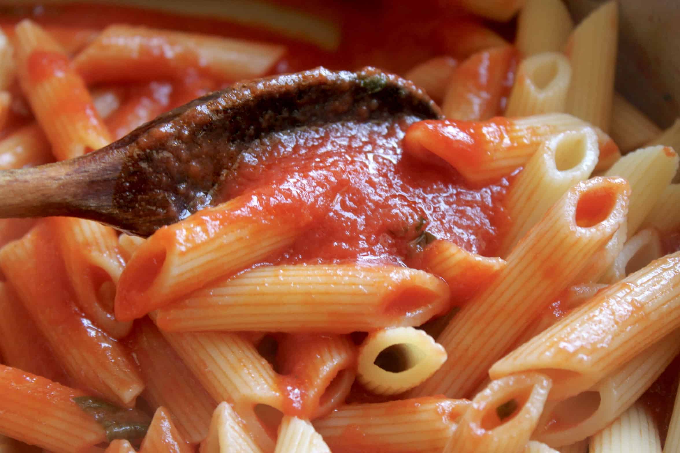 mixing sauce with penne pasta