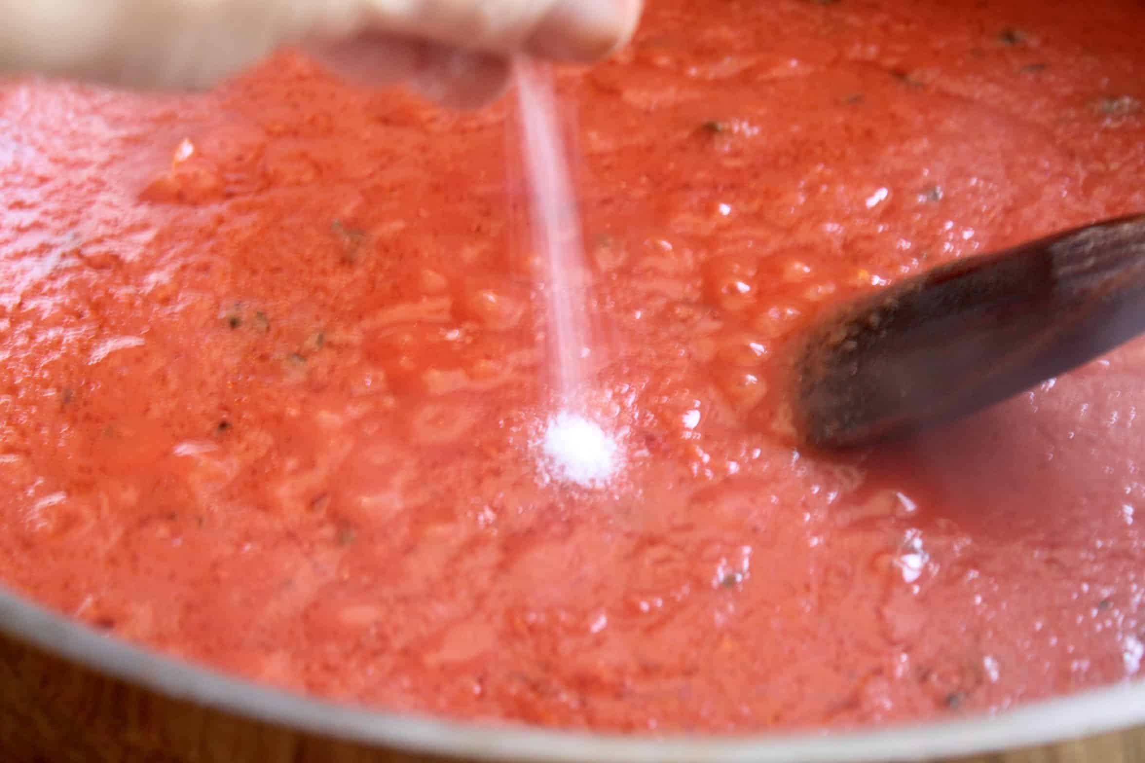 adding salt to tomato sauce