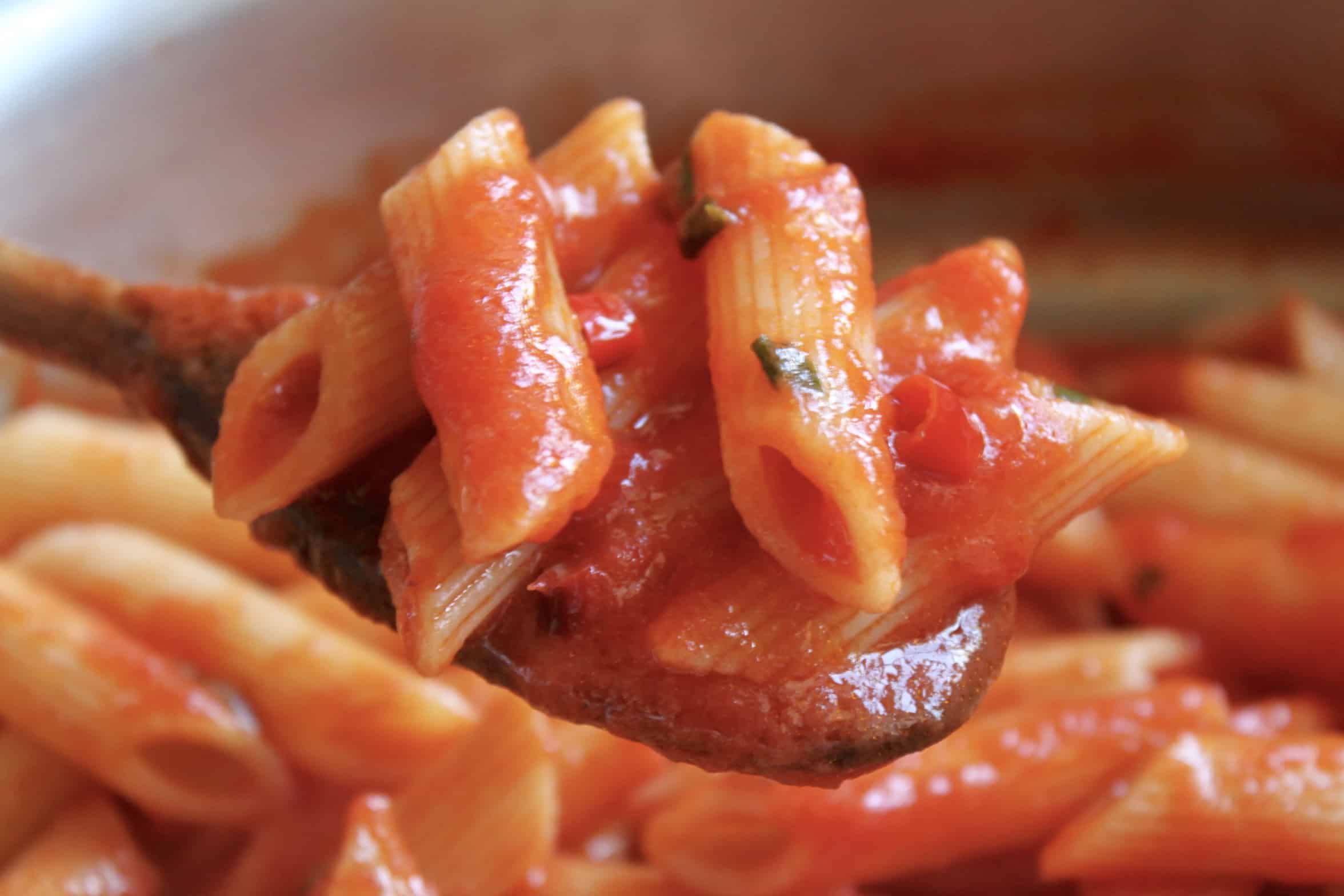 mixing sauce with penne pasta