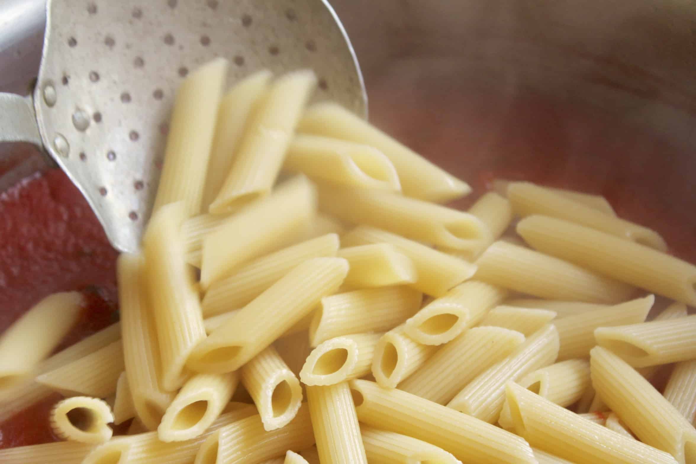 adding pasta to arrabbiata sauce