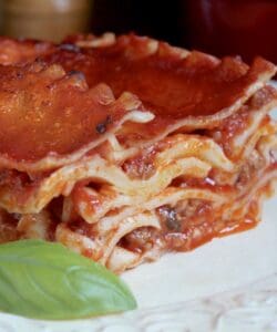 lasagna on a plate with a basil leaf