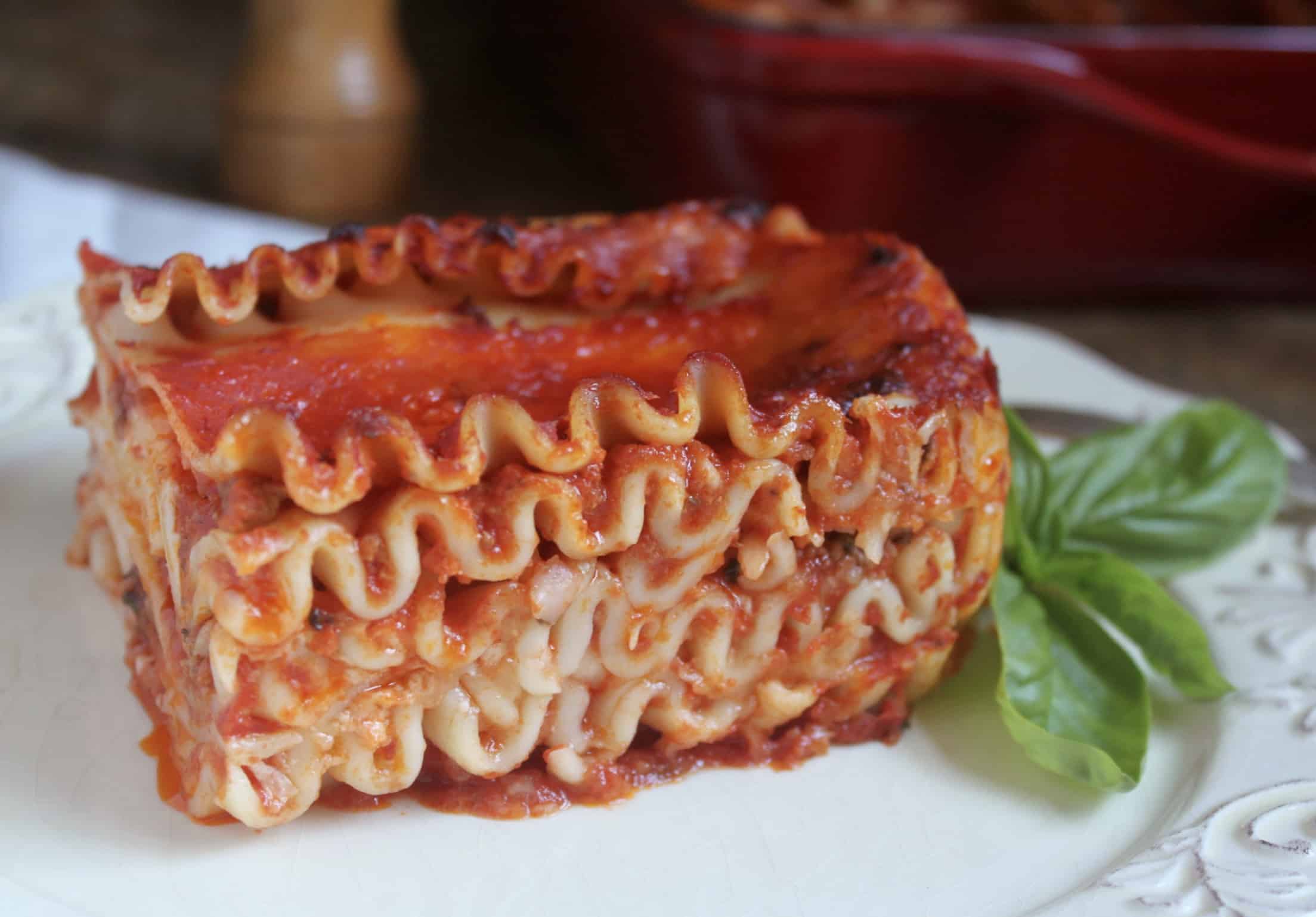 lasagna on a plate with a basil leaf