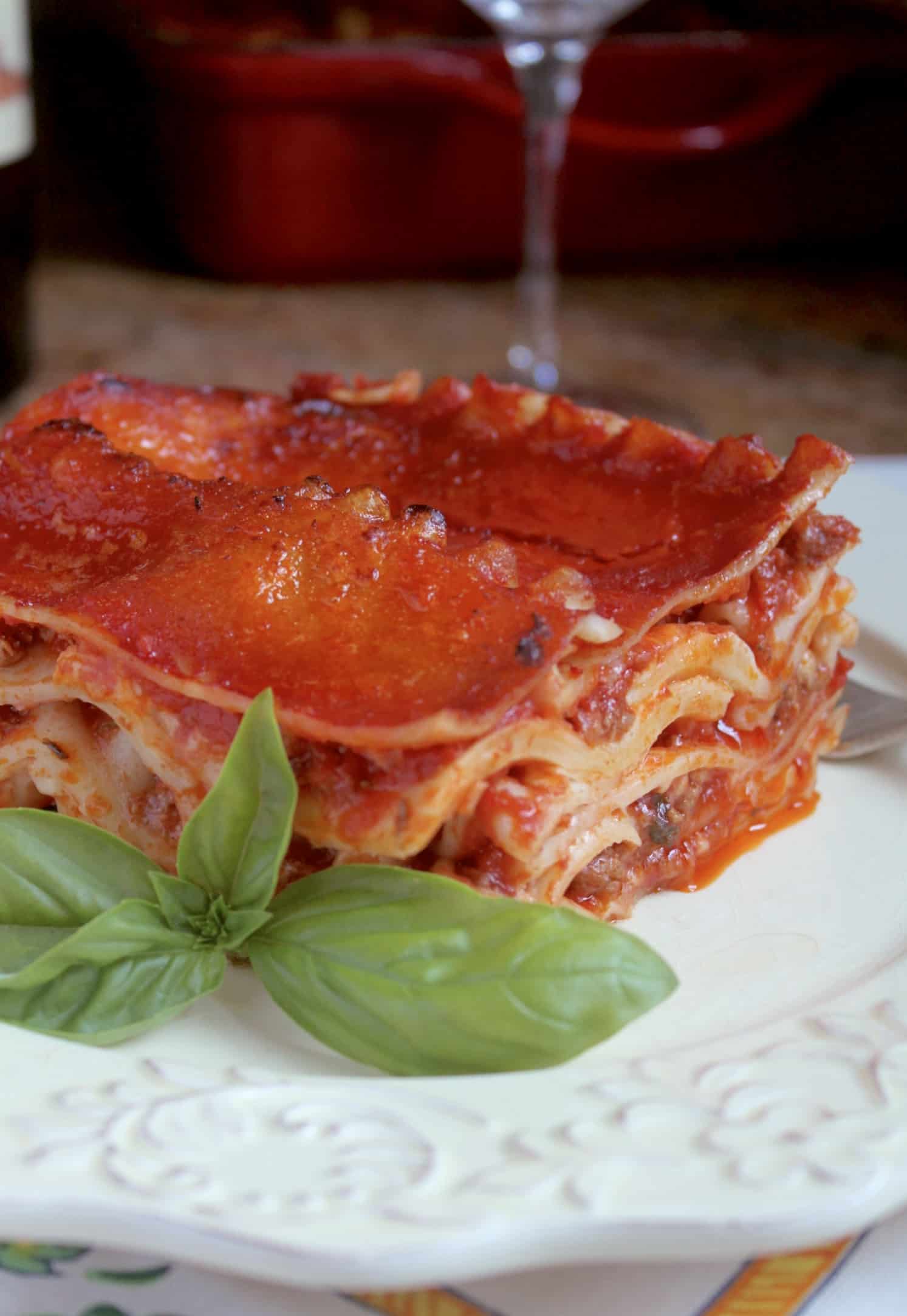 Lasagna on a plate with a sprig of basil