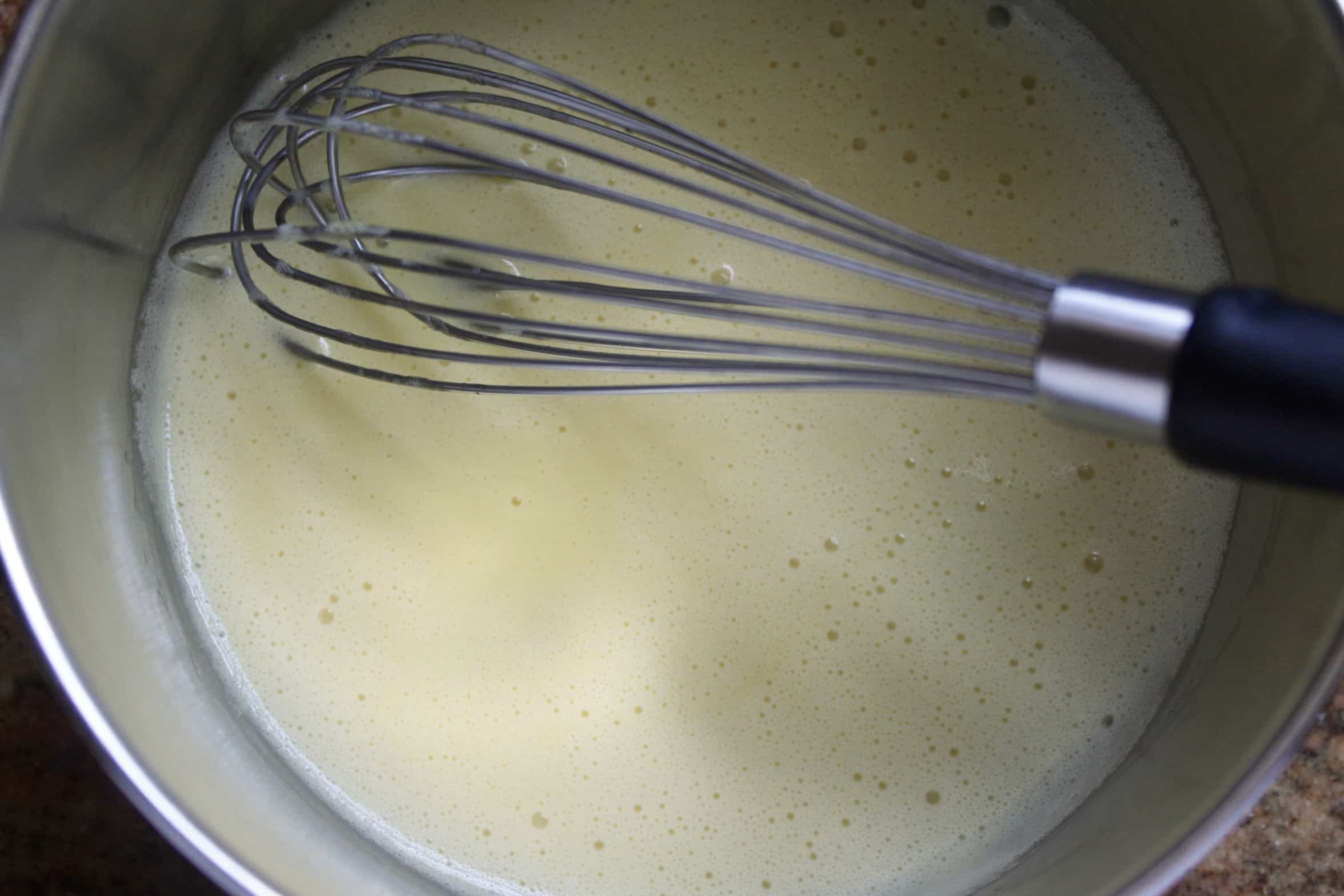 whisking egg yolk, cream and sugar in pot
