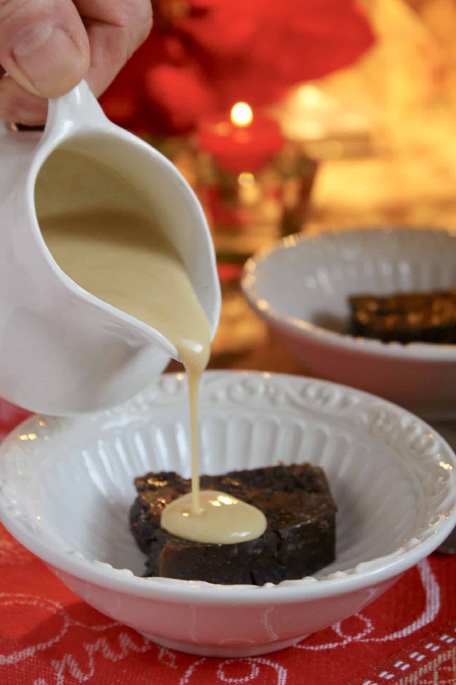 pouring brandy sauce on Christmas pudding in bowl