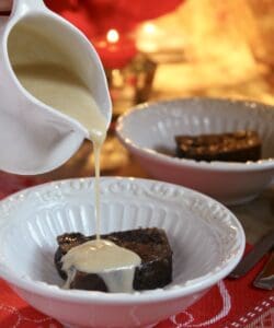 pouring brandy sauce on Christmas pudding in bowl