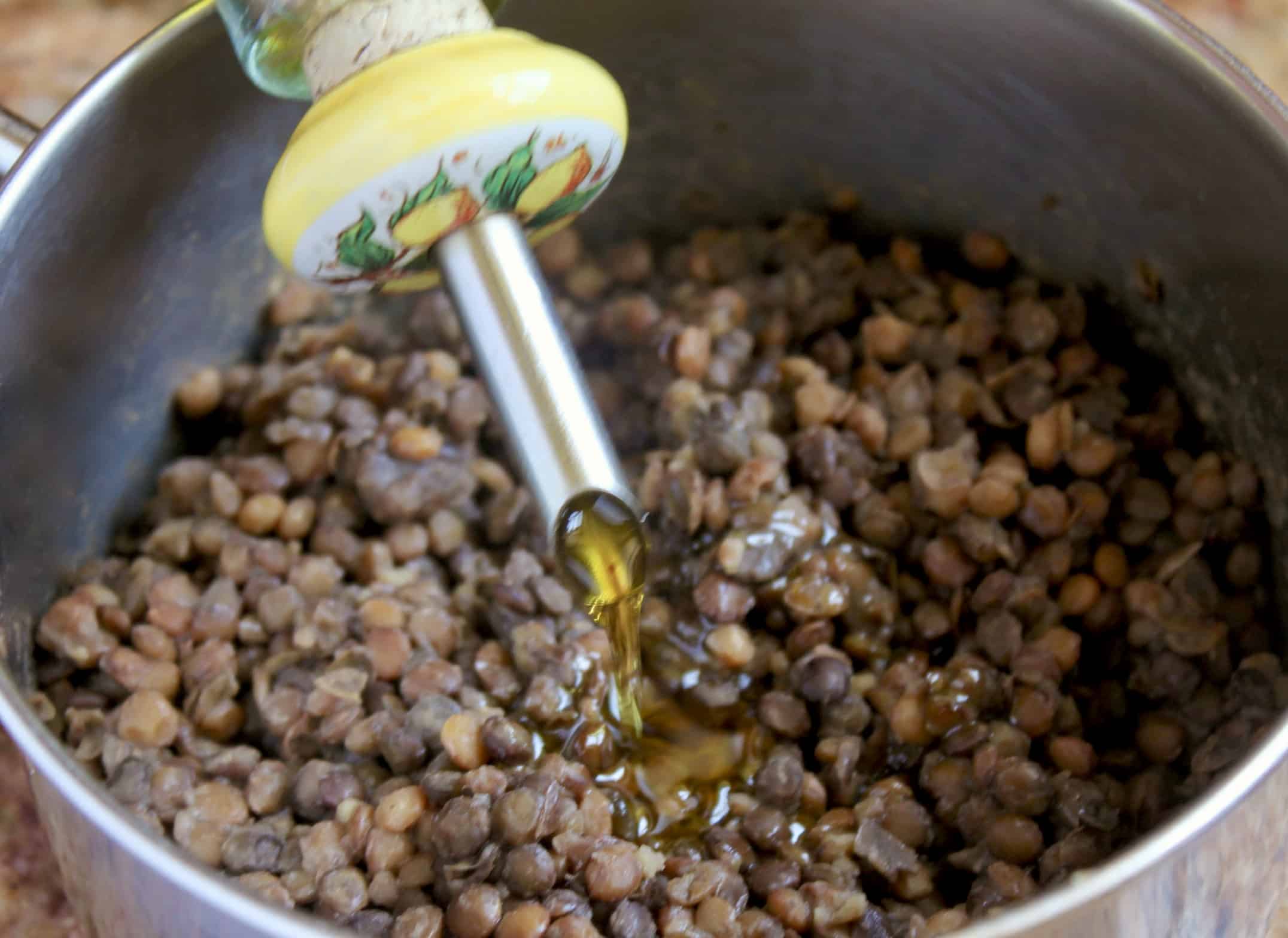adding olive oil to the cooked legumes
