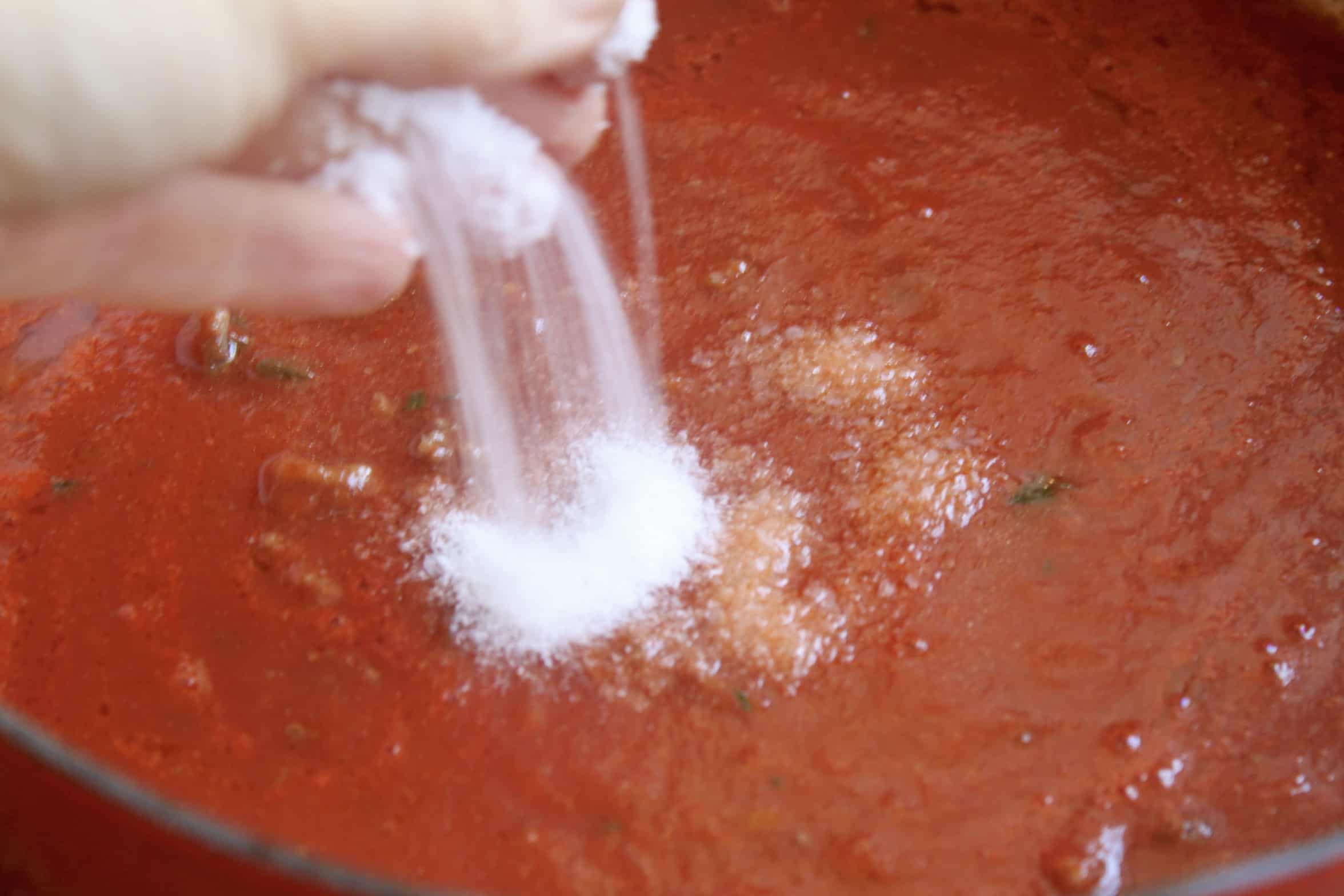 adding salt to the tomato sauce