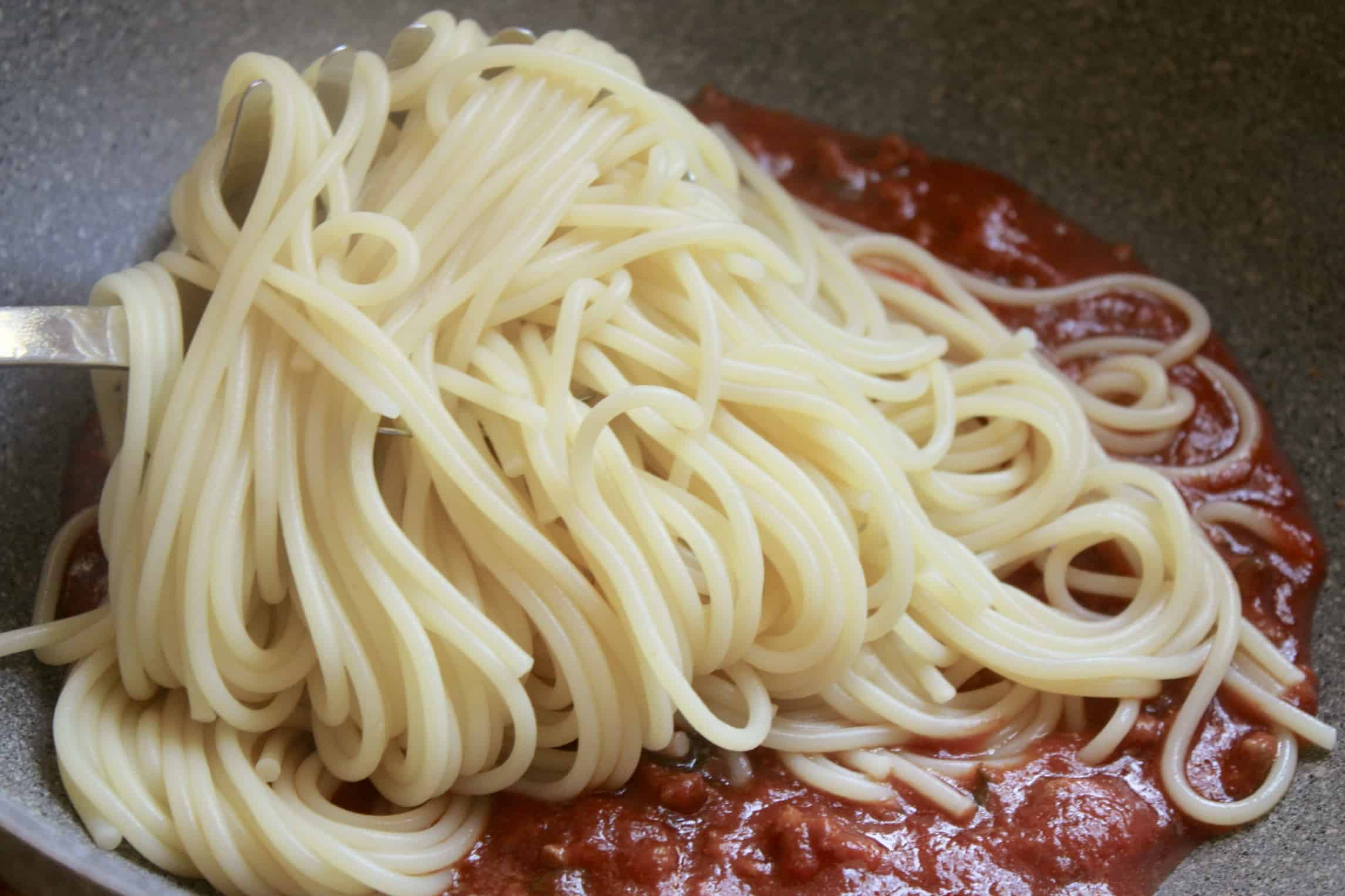 adding spaghetti to the sauce