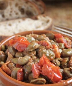 fava beans recipe with tomatoes in a bowl with bread