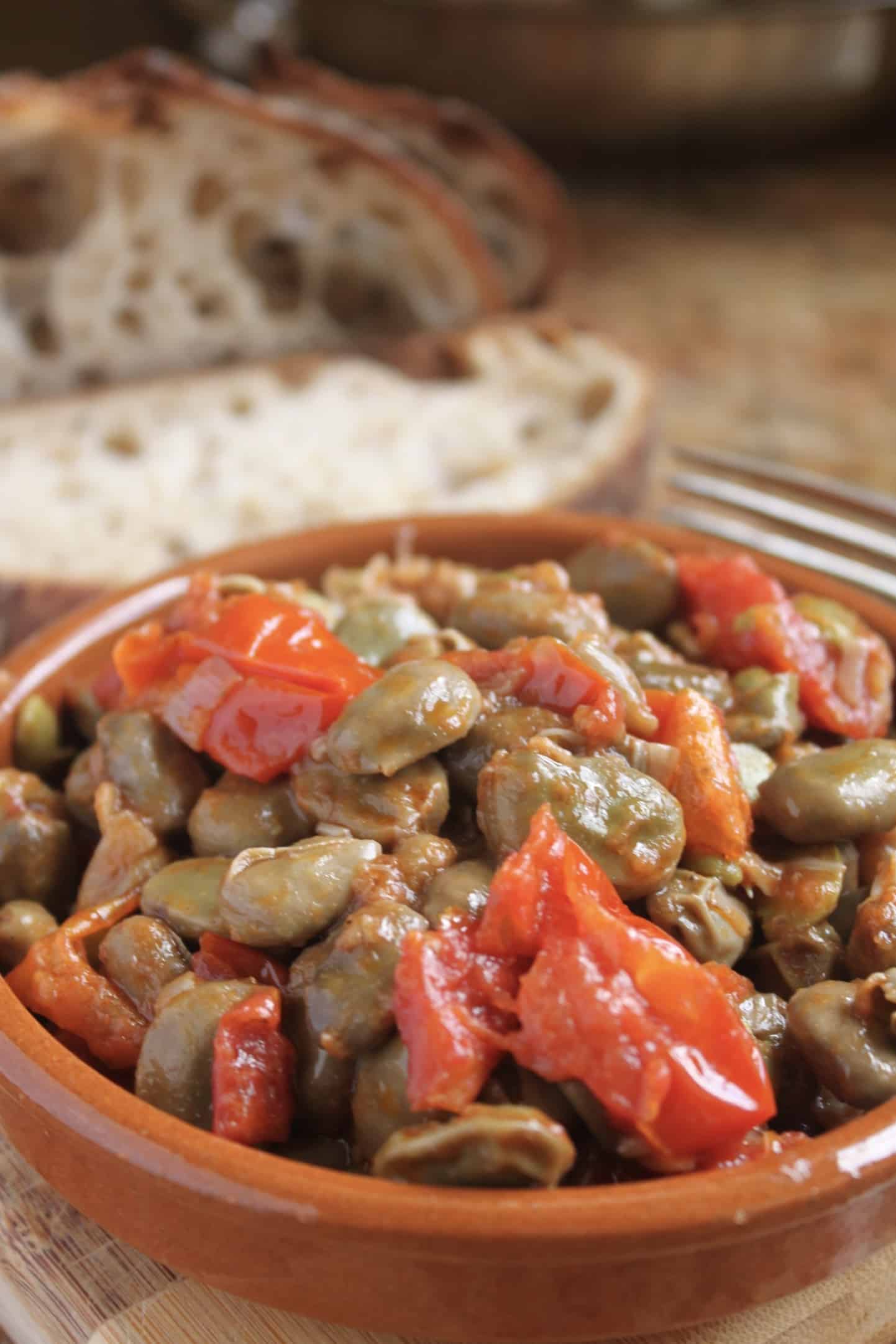 fava beans and tomatoes in a bowl with bread