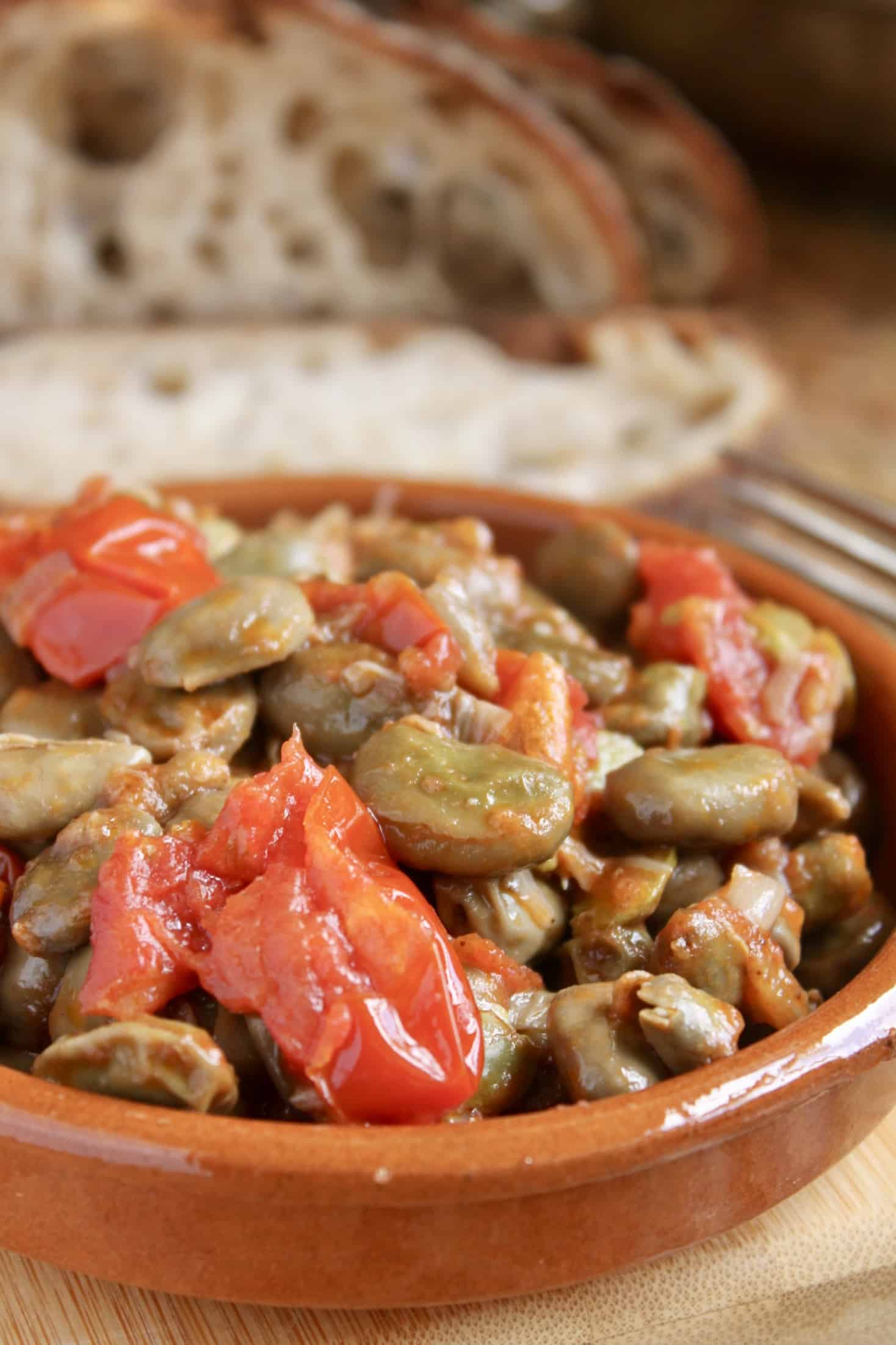 fava beans and tomatoes in a bowl with bread