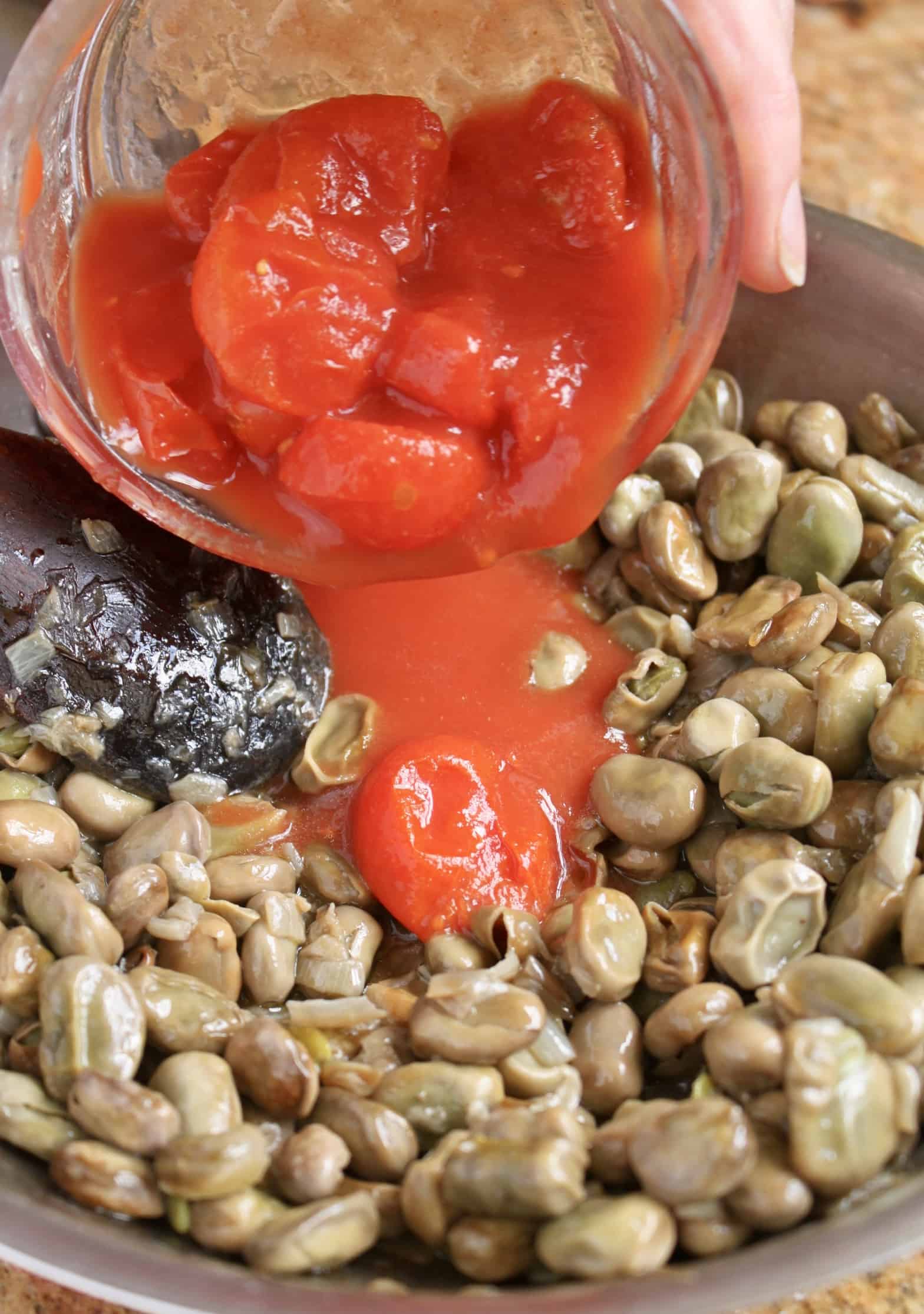 adding tomatoes to broad beans