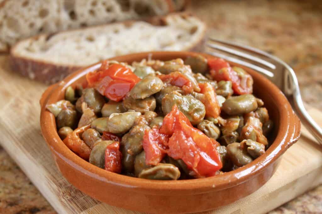 fava beans and tomatoes in a bowl with bread